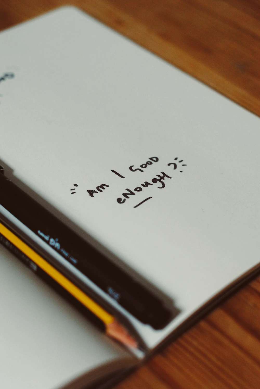 Notizblock mit der Frage ‚Am I good enough?‘ und zwei Stiften